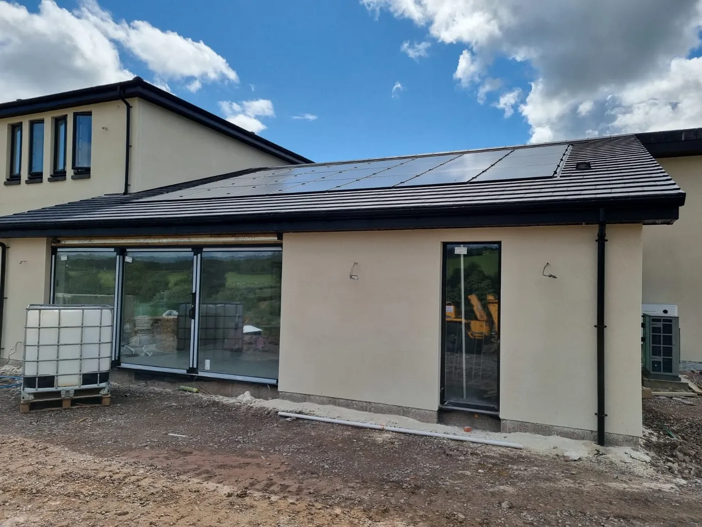 Roof-integrated solar array on the completed new-build home, with the air source heat pump alongside